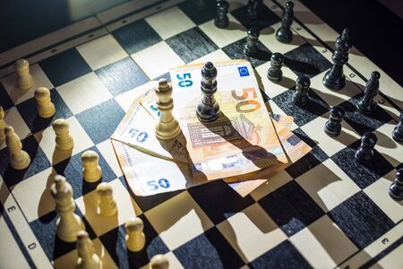 Top view of chessboard with arranged pieces, money with kings on top, agreement conceptの写真素材