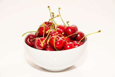 Red cherries inside a white cup on a white backgroundの写真素材