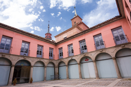 AlcalÃ¡ de Henares, Spain - June 18, 2022: Internal courtyard of the Cervantes Institute of AlcalÃ  de Henares and in the background the bell towers of the Parroquia Santa MarÃ­a la Mayorのeditorial素材