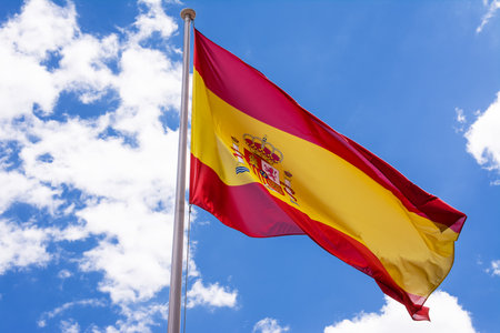 Spanish flag in the wind and with blue sky and clouds backgroundの写真素材
