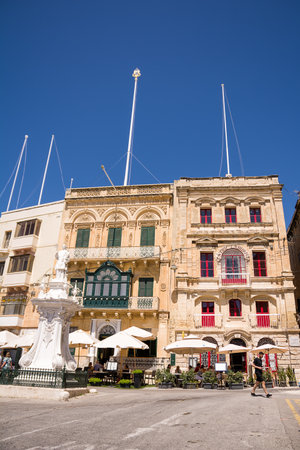 Vittoriosa, Malta - 17 June 2023: Umbrellas with bar tables in the square in Vittoriosa under the buildingsのeditorial素材