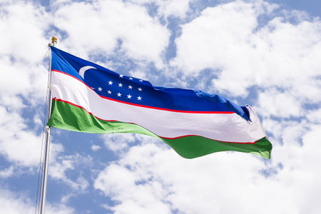 National Flag of Uzbekistan Fluttering in the Breeze with Cloudy Sky Backgroundの写真素材