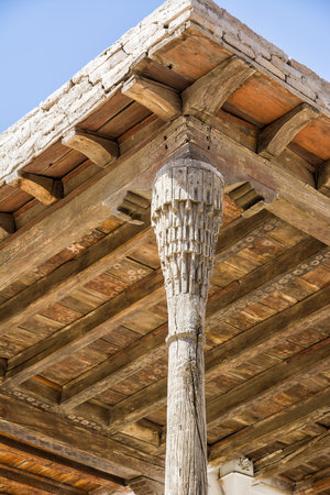 A Detail of a wooden column and raw timber ceiling in a historic palace in Khiva, Uzbekistanの写真素材