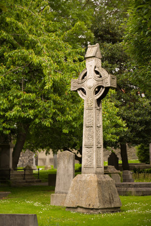 Beautiful Celtic cross in a green area surrounded by lush grass and trees