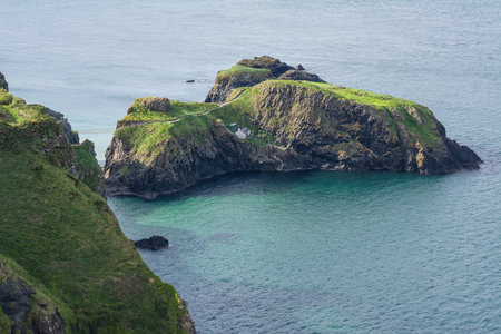 Tourists crossing Carrick a Rede rope bridge in Northern Ireland dramatic coastal scenery and...
