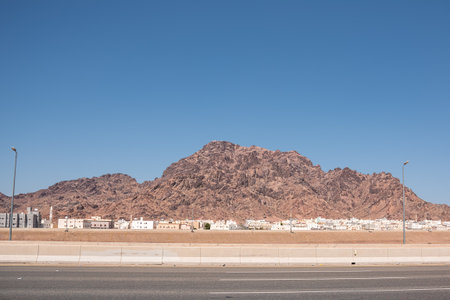 Rocky barren mountain with white low rise houses of a small town at its baseの写真素材