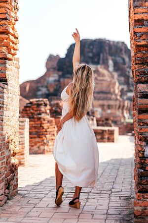 Higher. Young woman posing beside ancient ruins in Asia. Copy spaceの写真素材