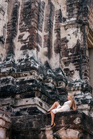 Travel far. Young woman posing beside ancient temple in Asia. Copy space in upper partの写真素材