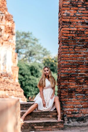 Adventure Time. Young woman posing beside ancient ruins in Asia. Copy space in upper partの写真素材