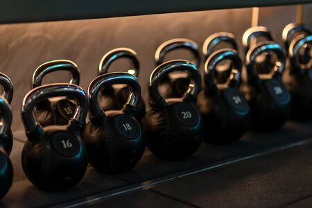 For you to choose. Stylish kettlebells weights made of black leather and iron lying in a row on the shelf in workout gym. Sport, lifting, healthy lifestyle concept. Horizontal shot.の写真素材