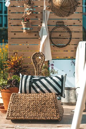 Relax here. Summer outdoor composition of big rattan chair with pillow and ceramic pots with plants. Stylish trendy eco natural exterior design. Outdoor decor. Vertical shotの写真素材