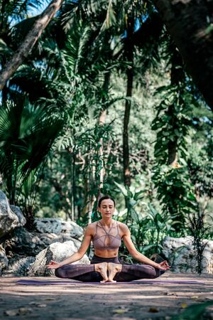 Center your body and mind. Full-length shot of caucasian woman sitting in Butterfly pose, Baddha Konasana while practicing yoga outdoors, in a garden. Healthy lifestyle and relaxation conceptの写真素材