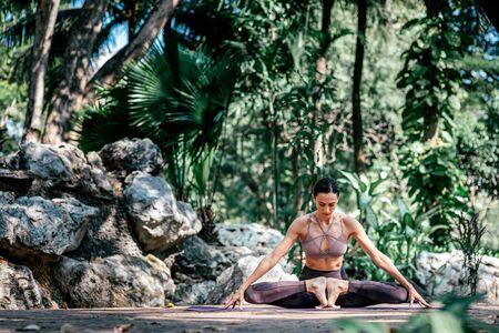 Stretch the possibilities. Full-length shot of caucasian woman sitting in Butterfly pose, Baddha Konasana while practicing yoga outdoors, in a garden. Healthy lifestyle and relaxation conceptの写真素材