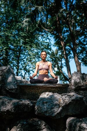 Full-length shot of caucasian woman sitting in Easy Seated pose, Sukhasana while practicing yoga...