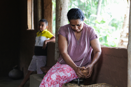 A mother grating a coconut to prepare lunchのeditorial素材