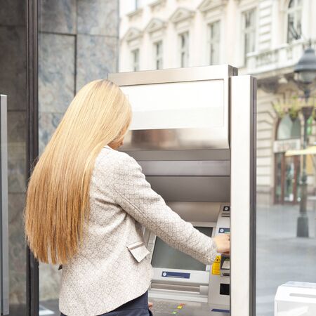 Young Woman using Bank ATM cashe machine on the streetの写真素材