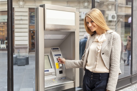 Young Woman using Bank ATM cashe machine on the streetの写真素材