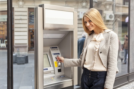 Young Woman using Bank ATM cashe machine on the street