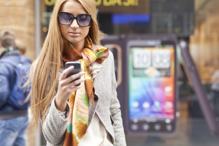 Young Woman with smartphone walking on street, downtown. In background is blured streetの写真素材