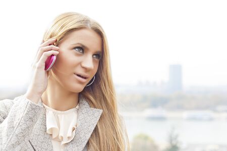 Young Woman with smartphone walking outdoor, downtown  In background is blured cityの写真素材
