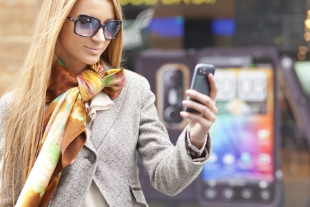 Young Woman with mobile phone walking background is blured cityの写真素材