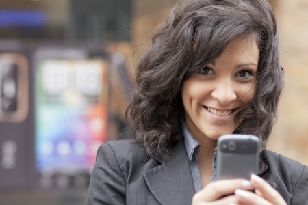 Young Woman with mobile phone walking background is blured cityの写真素材