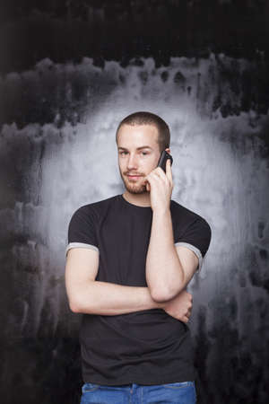Young Man using smartphone for call, studio shot on black backgroundの写真素材