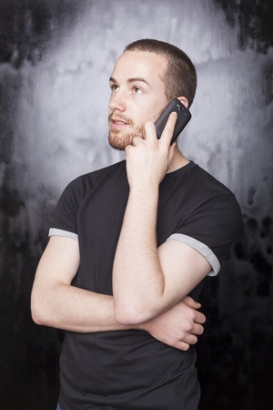 Young Man with smartphone, black backgroundの写真素材