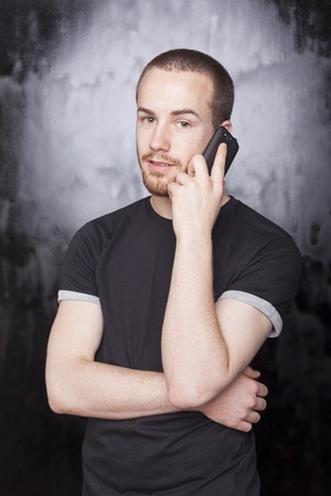 Man with smartphone talking and smiling, studio shot on black backgroundの写真素材