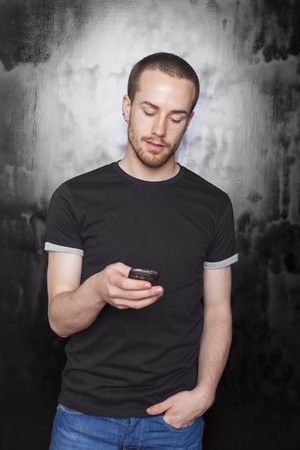 Young Men with mobile phone typing SMS, studio shot on black backgroundの写真素材