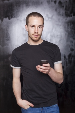 Men with cellphone typing SMS, studio shot on black backgroundの写真素材