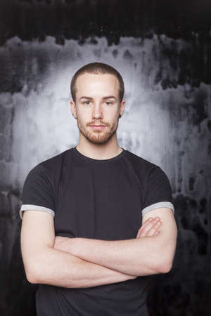 Good Looking Young Man Portrait on black in black t-shirt, Arm-Crossの写真素材