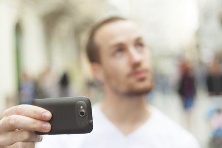 Man photographer with mobila phone make photo on streetの写真素材