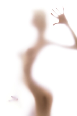 Blurred glass of bathroom hiding sexy female body silhouetteの写真素材