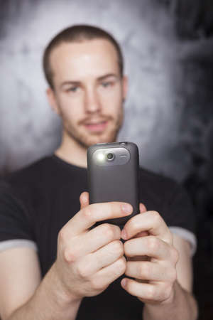 Young Man with smartphone, studio shot on black background, flash is onの写真素材