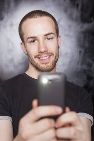 Young Man with smartphone, studio shot on black backgroundの写真素材