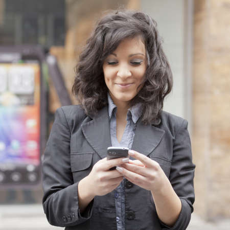 Young Woman with mobile phone walking background is blured cityの写真素材
