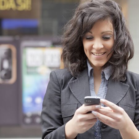 Young Woman with mobile phone walking background is blured cityの写真素材