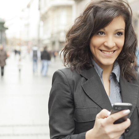 Young Woman with smartphone walking on street, downtown. In background is blured street, looking in front
の写真素材