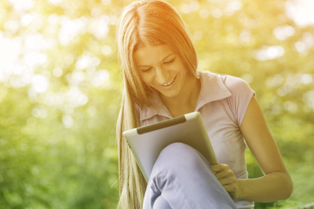 Beautiful Young Woman With Tablet Computer In Parkの写真素材