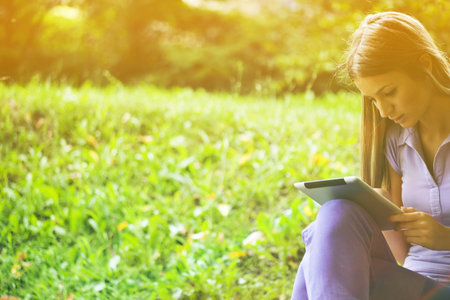 Beautiful Young Woman With Tablet Computer In Parkの写真素材