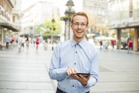 Goodlooking businessman with tablet computer on urban streetの写真素材