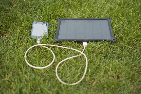 Use of renewable energy - Mobile Phone Chargers on grass in nature with Sunの写真素材