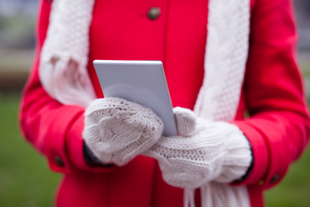 Woman in wool gloves hold tablet smart-phone. Cold Weatherの写真素材