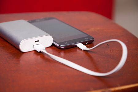 Mobile Phone Charging With Power Bank on wooden table