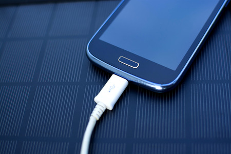 Use of renewable energy - Mobile Phone Chargers on grass in nature with Sunの写真素材