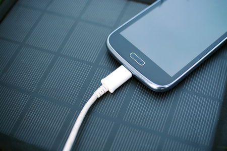 Use of green renewable energy - Mobile Phone Chargers on grass in nature with Sunの写真素材