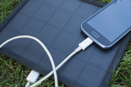 Use of renewable energy - Mobile Phone Chargers on grass in nature with Sunの写真素材