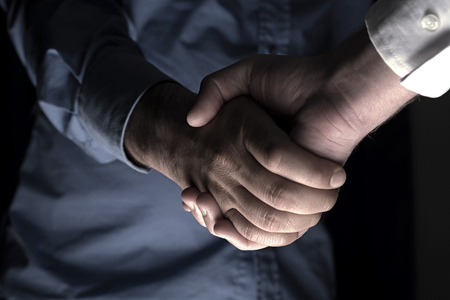 Handshaking of two business people. Partnership - Teamwork. Greeting, Form Of Communication. Light in scene come from down.の写真素材