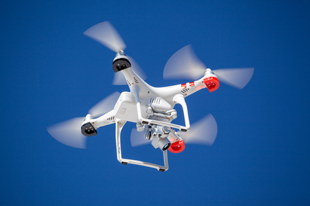 Quadrocopter drone with camera on blue clear sky recording photo and videoの写真素材